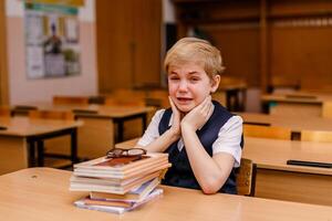 Little schoolboy crying at his desk in a classroom photo