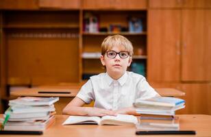 Student boy reading a book and looking very surprised in his school classroom photo