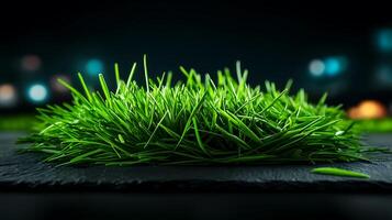 Lush green grass on a dark slate surface with blurred colorful lights in the background photo