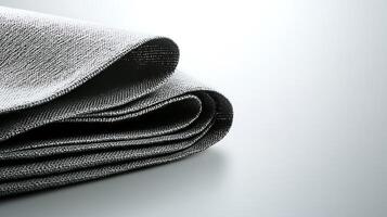 Close-up of a folded gray fabric on a smooth surface with subtle lighting effects photo