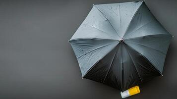A top-down view of a rain-soaked black umbrella resting on a gray surface with a yellow object nearby photo
