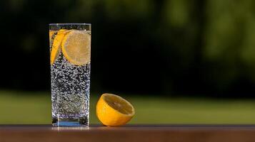 Refreshing glass of sparkling water with lemon slices on a wooden table in a sunny garden photo