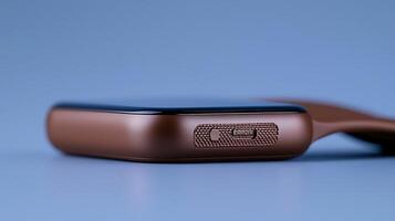 Close-up of a sleek brown smartphone with a textured side button against a soft blue background photo