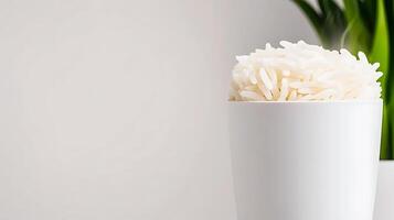 Steaming bowl of rice placed on a minimalist table with a green plant in the background photo