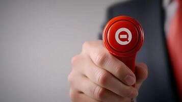 Close-up of a hand holding a red button with a symbol, indicating a decision-making moment photo