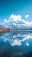 Snowy mountain peaks reflecting in a clear blue lake under a cloudy sky photo