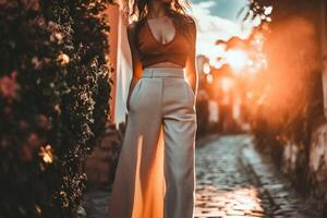 A woman in a white pantsuit and top standing in a cobblestone street photo