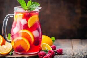 Refreshing raspberry and orange summer drink with ice and mint in a pitcher photo