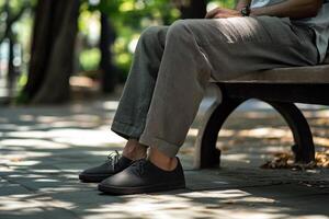 A person sitting on a bench wearing black shoes photo