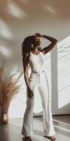 A woman in white pants and a top standing in front of a window photo