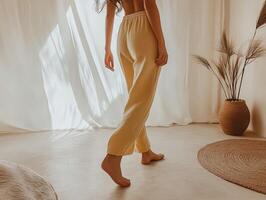 A woman in yellow pants and top walking in a room photo