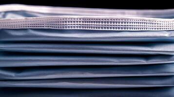 Close-up view of stacked blue surgical masks highlighting texture and folds, set against a dark background photo