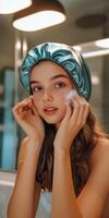 Young woman applying skincare while wearing a silk bonnet in a bathroom photo