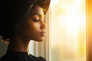 Woman wearing silk bonnet gazing out window during sunset photo