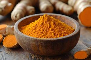 Turmeric powder in wooden bowl with turmeric rhizomes on rustic table photo