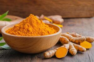 Turmeric powder in wooden bowl and fresh turmeric root on rustic table photo