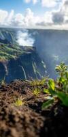 Lush landscape around a volcanic crater with smoke rising in the distance photo