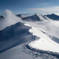 Snowy mountain peak with clouds below photo