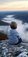 Child gazes at sunset over mountains photo