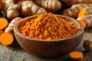Turmeric powder in wooden bowl with turmeric rhizomes on rustic table .. photo