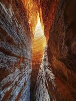 A narrow canyon with a light coming through it photo