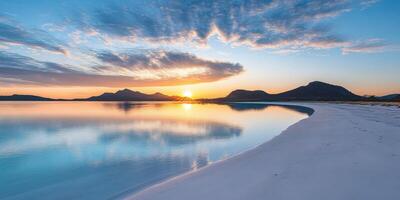 A beautiful sunset over a beach with water and mountains photo