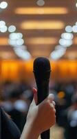 A woman holding a microphone in front of a crowd photo