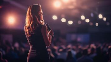 A woman is standing in front of a crowd at a conference photo