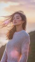 A woman in a sweater standing on a hill with the sun in the background photo
