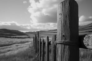 A black and white photo of a fence in the middle of a field