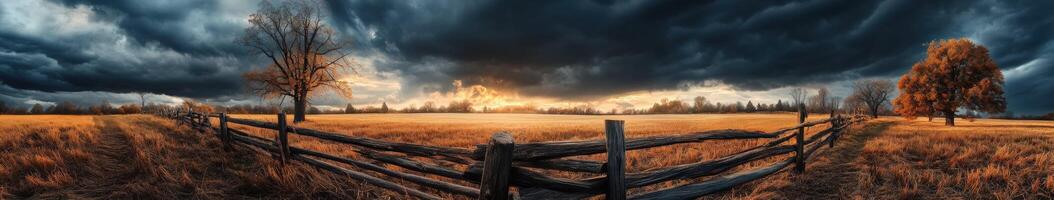 A field with a fence and trees under a stormy sky photo
