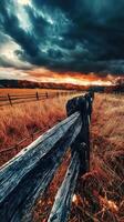 A wooden fence in a field with a stormy sky photo