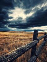 A wooden fence in a field with storm clouds in the background photo