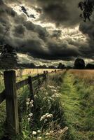 A field with a wooden fence and a stormy sky photo