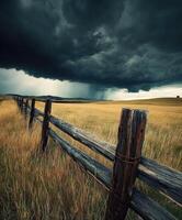 A fence and a stormy sky in the middle of a field photo