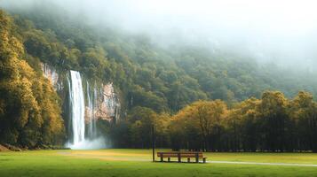 Serene waterfall cascading down rocky cliffs surrounded by lush greenery and misty mountains photo