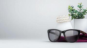 Stylish sunglasses placed on a soft fabric with decorative plants and accessories in a minimalist setting photo