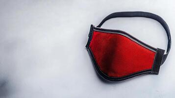 Red fabric mask resting on a smooth surface with a soft background, suitable for health awareness photo
