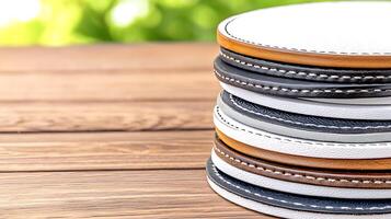 Stacked coasters in various colors resting on a wooden table with a blurred green background photo