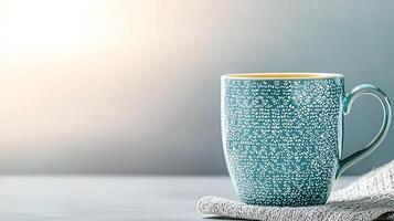A beautifully patterned teal coffee mug sits on a soft linen napkin against a serene background photo