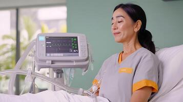 Woman in hospital attire relaxes while monitoring health metrics on a medical device photo