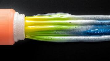 Vibrant toothpaste flowing from a tube against a dark background, showcasing vivid colors and texture photo