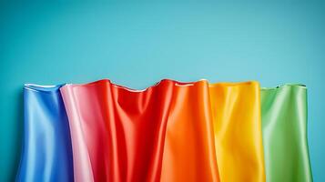 Vibrant waves of colorful fabric draped against a soft blue background, showcasing texture photo