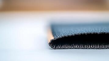 Close-up view of a textured fabric edge, showcasing its weave and color gradient against a blurred background photo