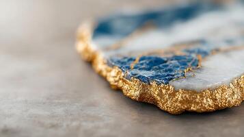 Close-up view of a blue and white marble coaster with a golden edge on a textured surface photo