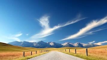 Serene gravel road stretching through a vast meadow with distant mountains under a clear sky photo