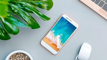 Smartphone displaying a beach wallpaper on a modern desk with a plant and mouse photo