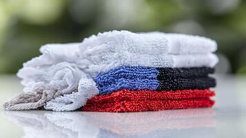 Stacked colorful cleaning cloths on a reflective surface with a blurred green background photo