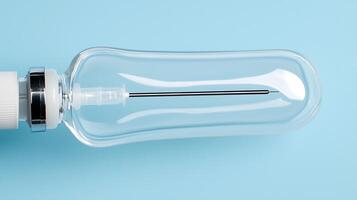 Transparent medical syringe on a light blue background, showcasing its design and functionality photo