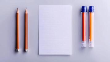 Two pencils and two markers beside a blank notepad on a minimalist gray background photo